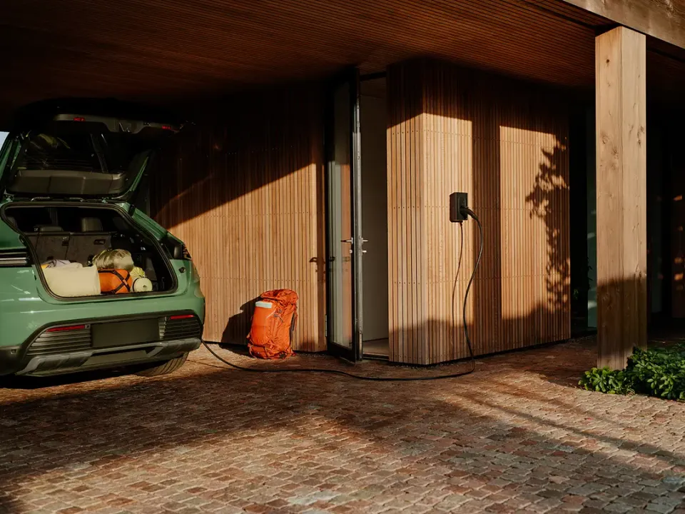 Zaptec Go-laddbox och elbil vid en villa med träfasad